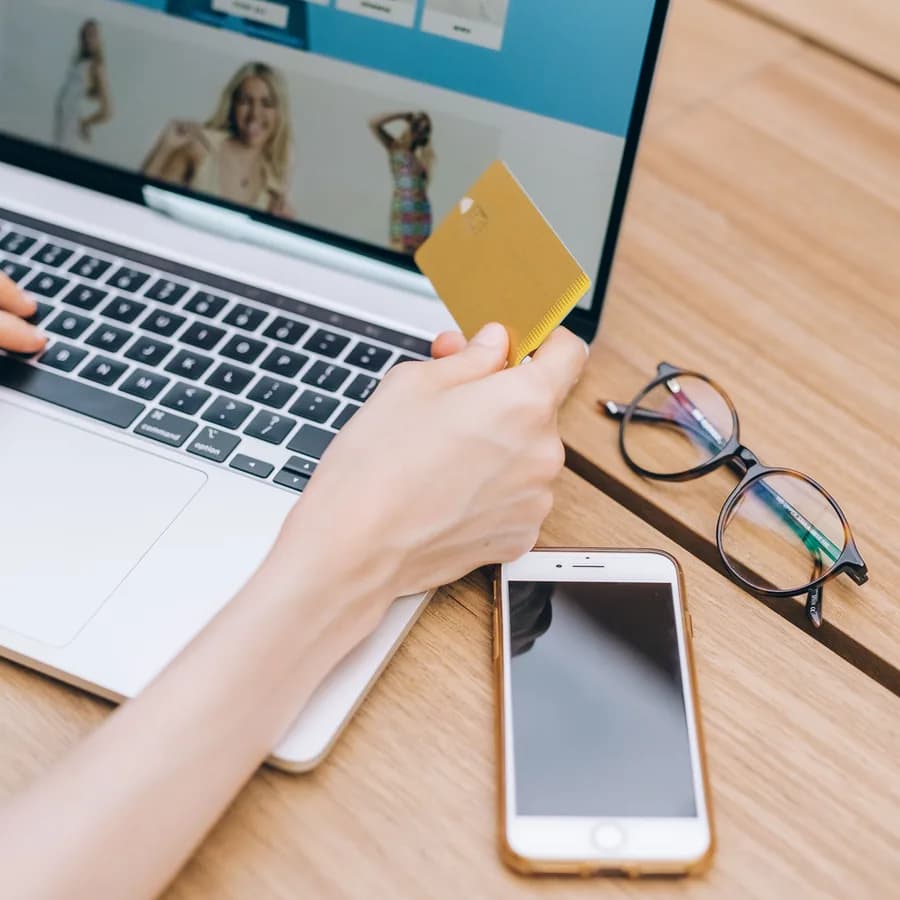 An online shopper holding a credit card while checking out on a laptop