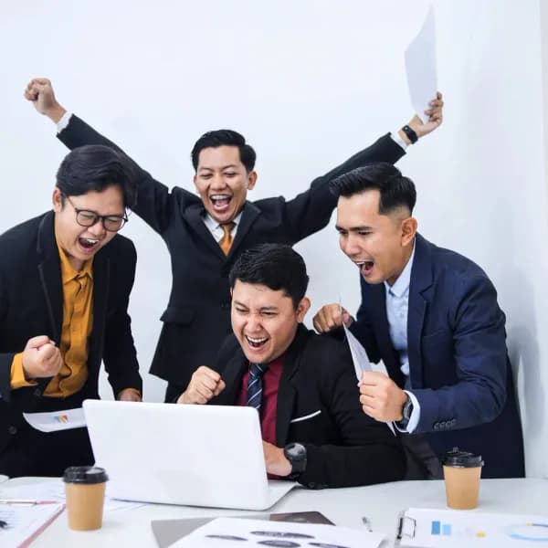 An offshore team celebrating a project win around a laptop