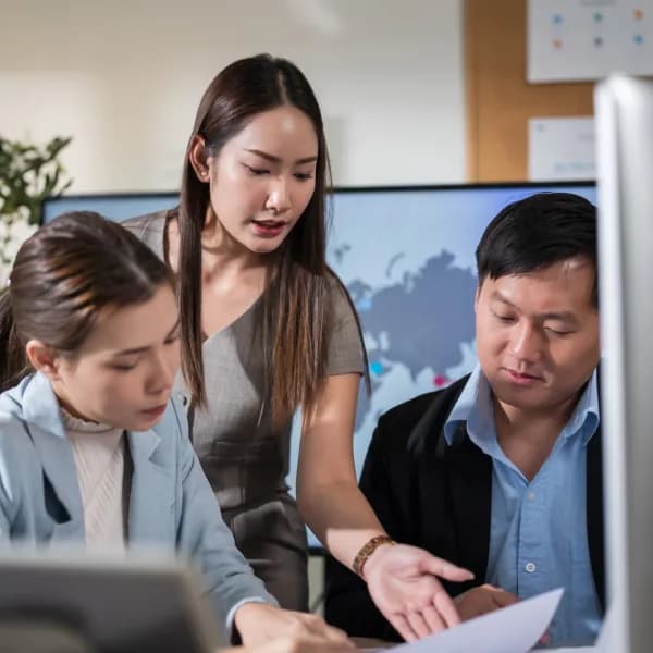 Team members reviewing work together at a shared monitor